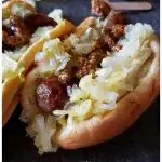 Amazing Beer Braised Bratwurst grilled and on a bun with homemade sauerkraut and course grain mustard