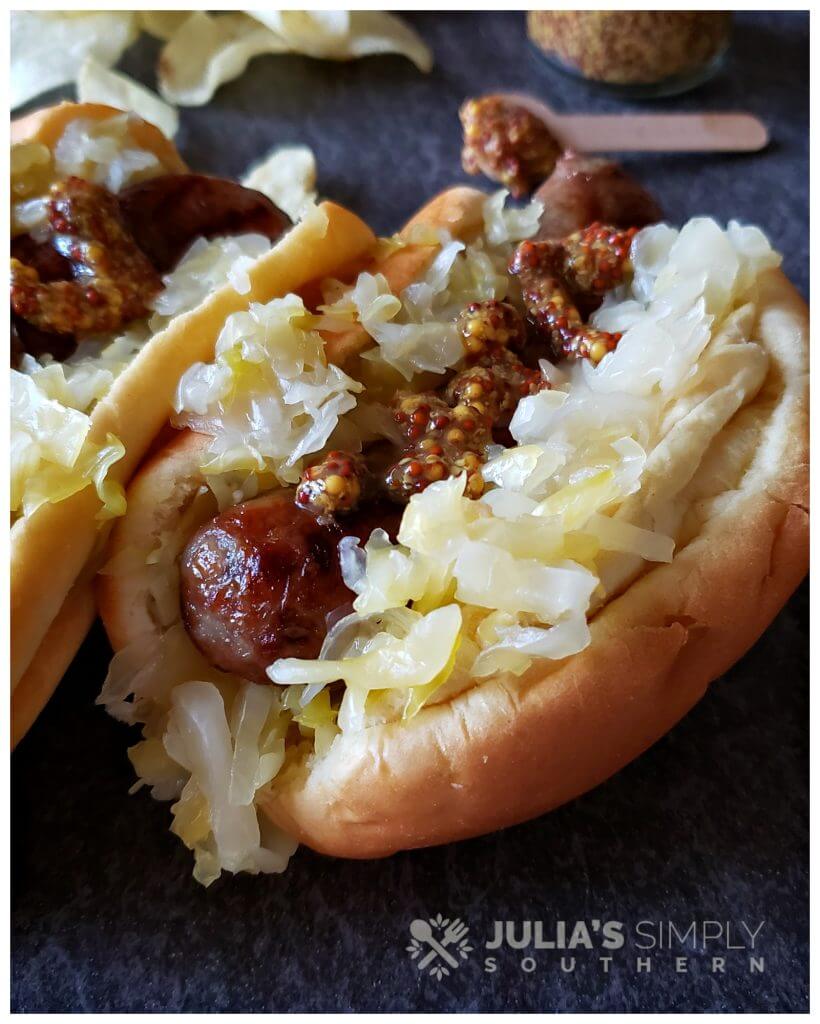 Amazing Beer Braised Bratwurst grilled and on a bun with homemade sauerkraut and course grain mustard