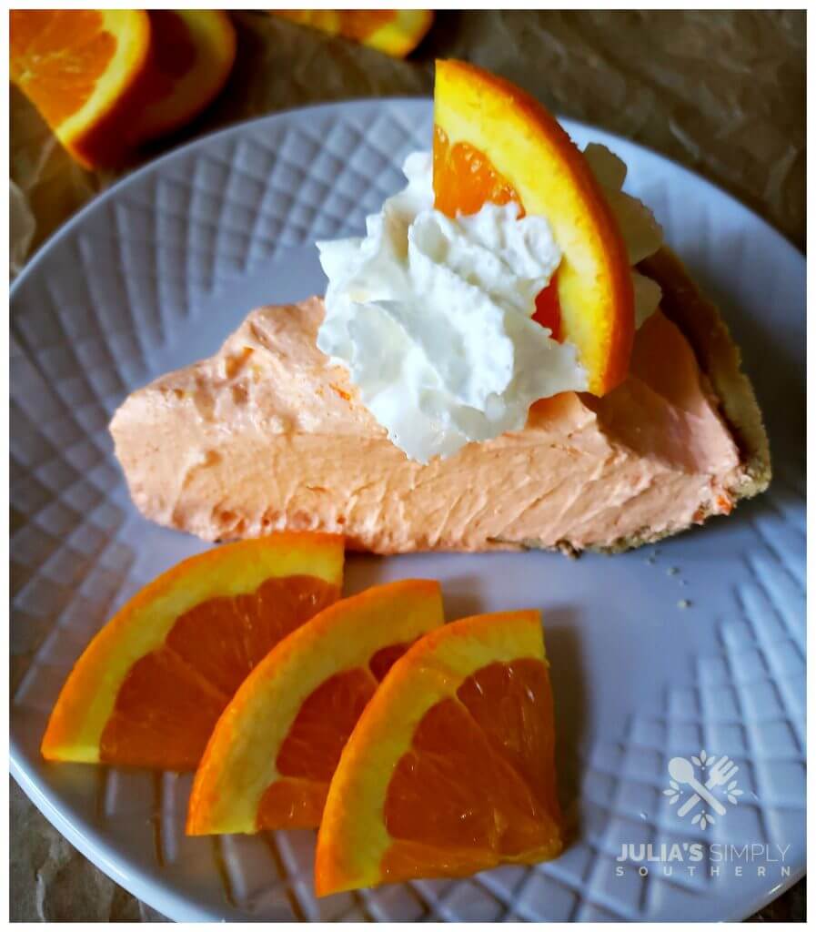 Orange Dreamsicle Chiffon Pie topped with whipped cream and an orange slice garnish on a plate