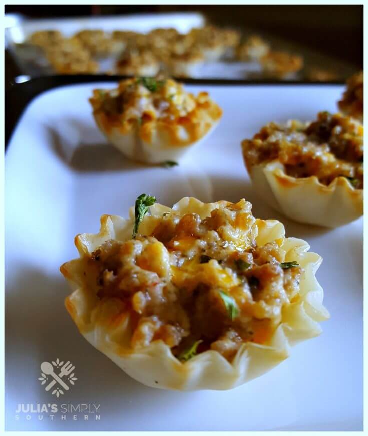 Spicy Sausage Tarts in Phyllo mini cups on a white platter for a Christmas and New Year party