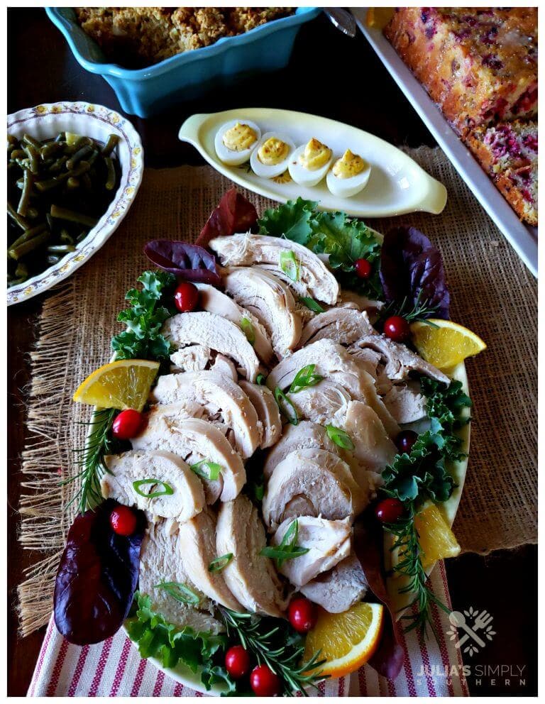 Crock Pot Turkey on a platter surrounded by Thanksgiving side dishes