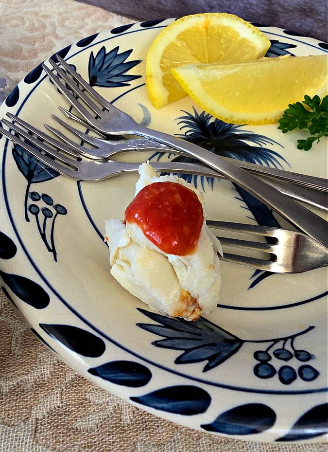 blue and white plate with SC palmetto design with appetizer forks, lemon wedges, and a serving of crab cocktail appetizer
