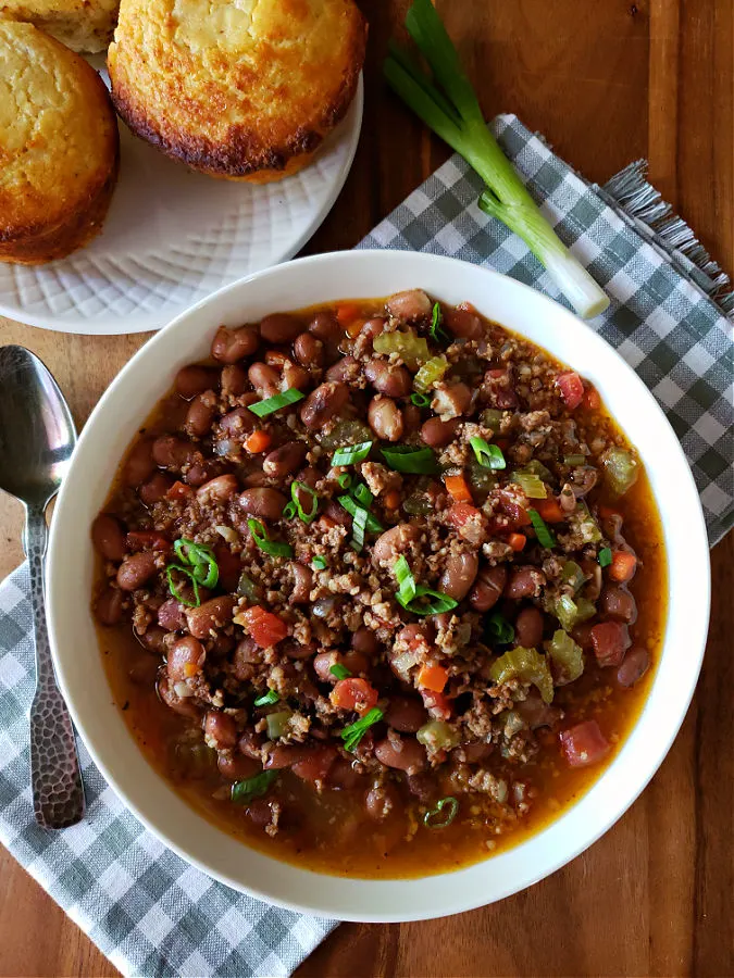 White bowl with savory bean soup made with cranberry beans and breakfast sausage