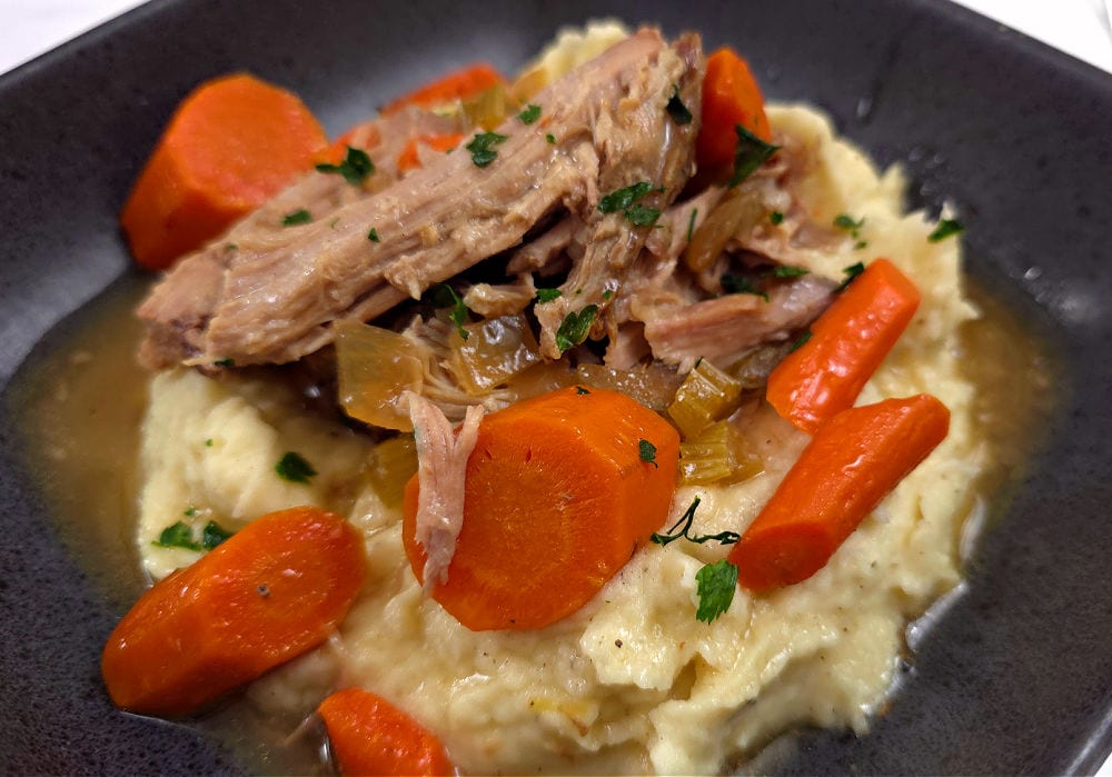 Mashed Potatoes topped with Crock Pot Pork Shoulder Roast with carrots and gravy on mashed potatoes