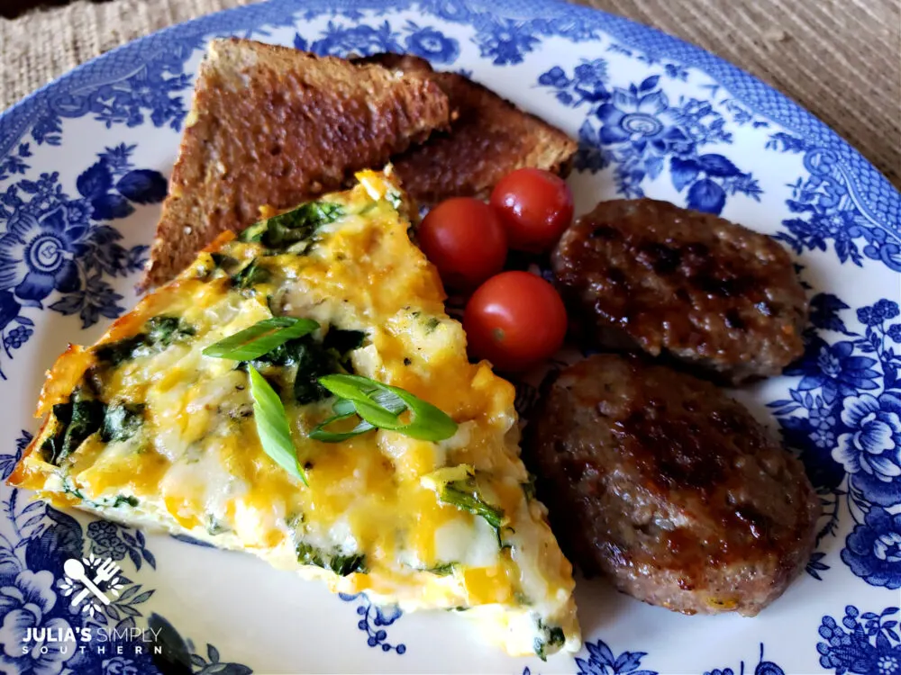 Crustless vegetable quiche recipe on a plate with cherry tomatoes, toasted bread and sausage patties