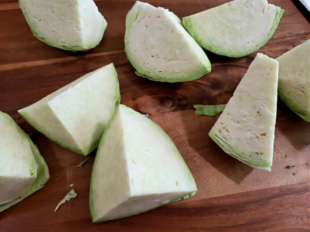 Cut wedges of green cabbage on a cutting board before cooking