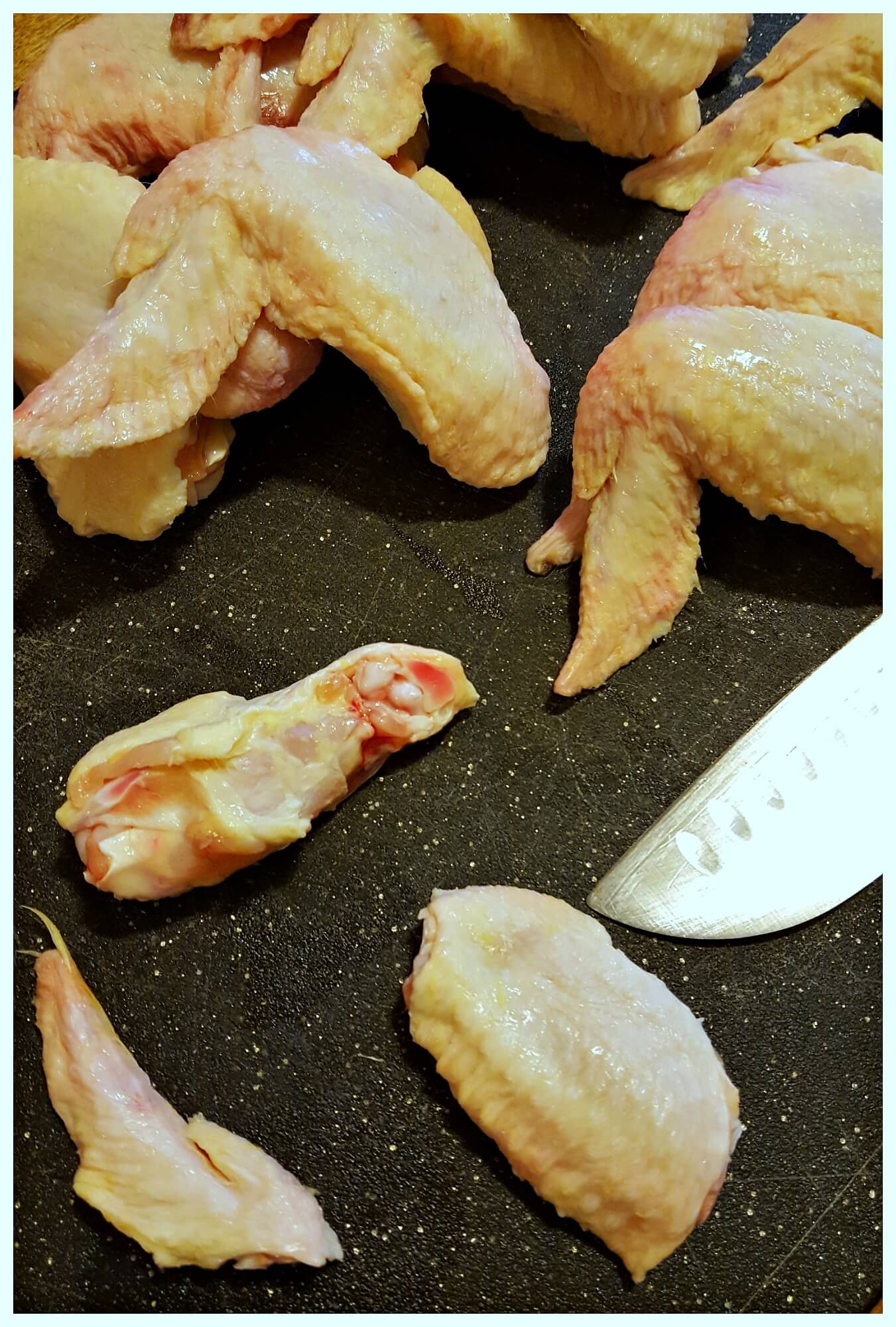Cutting up chicken wings to separate the drumette and flat pieces