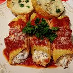 Beef manicotti with red sauce on a plate with a side of garlic cheese toast