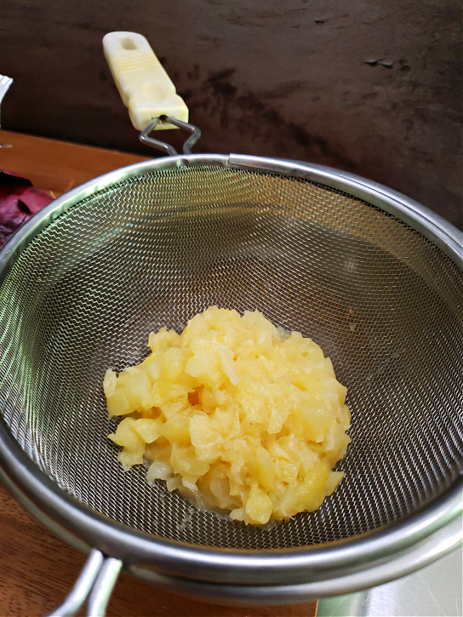 draining pineapple in a mesh strainer over a bowl