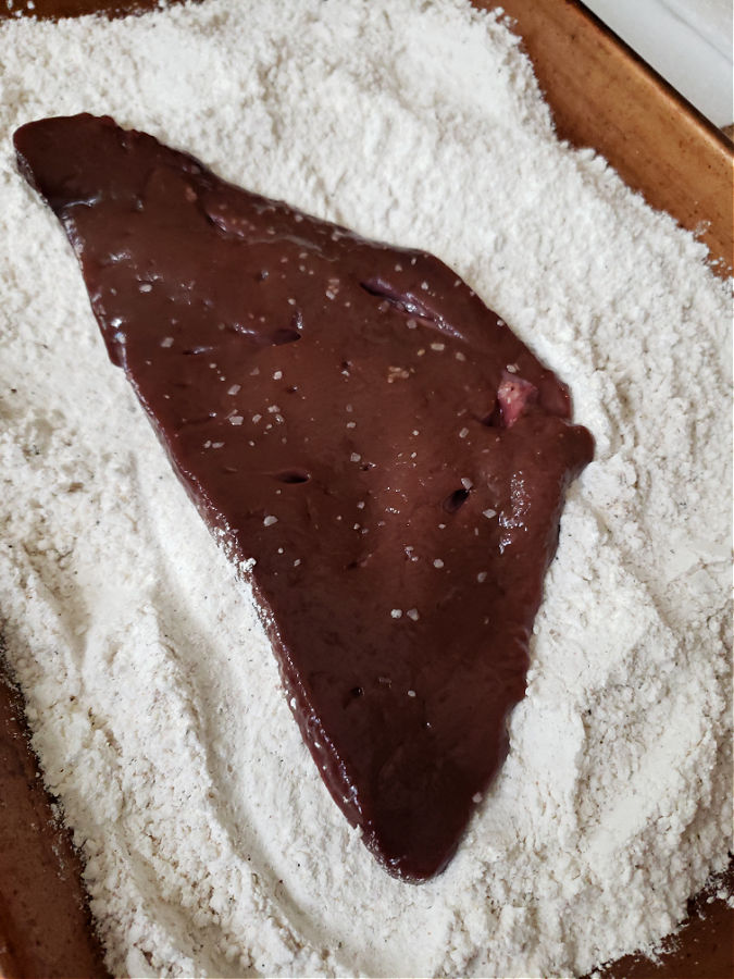 seasoned flour and slice of beef liver being dredged for cooking