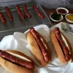 hot dog buns with crispy hot dogs cooked in an air fryer with topping options on a white tablecloth