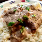 Easy Baked Cubed Beef Steaks served over rice and garnished with spring onions