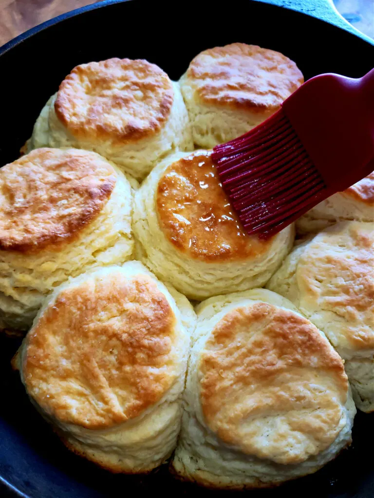 Brushing butter over fresh from the oven scratch made biscuits