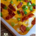 Easy Loaded Mashed Potato Casserole with cream cheese, sour cream, bacon, cheese and scallions in a vintage orange anchor hocking casserole dish