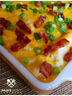 Easy Loaded Mashed Potato Casserole with cream cheese, sour cream, bacon, cheese and scallions in a vintage orange anchor hocking casserole dish