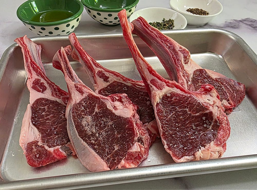 Lamb Chops on a prep pan with ingredients in the background to prepare a marinade