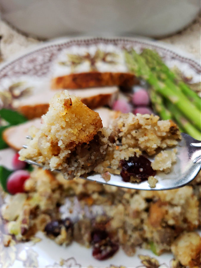 cornbread stuffing on a fork with plate of food in the background