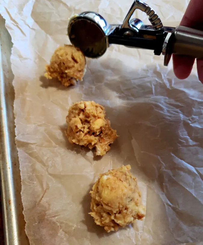 Scooping dough ball onto a lined baking sheet
