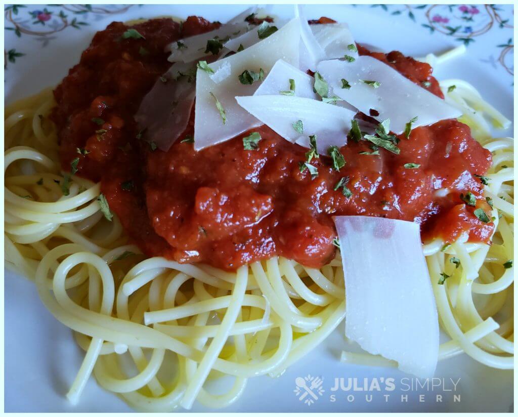 Spaghetti with marinara and Parmesan on a floral china plate garnished with parsley