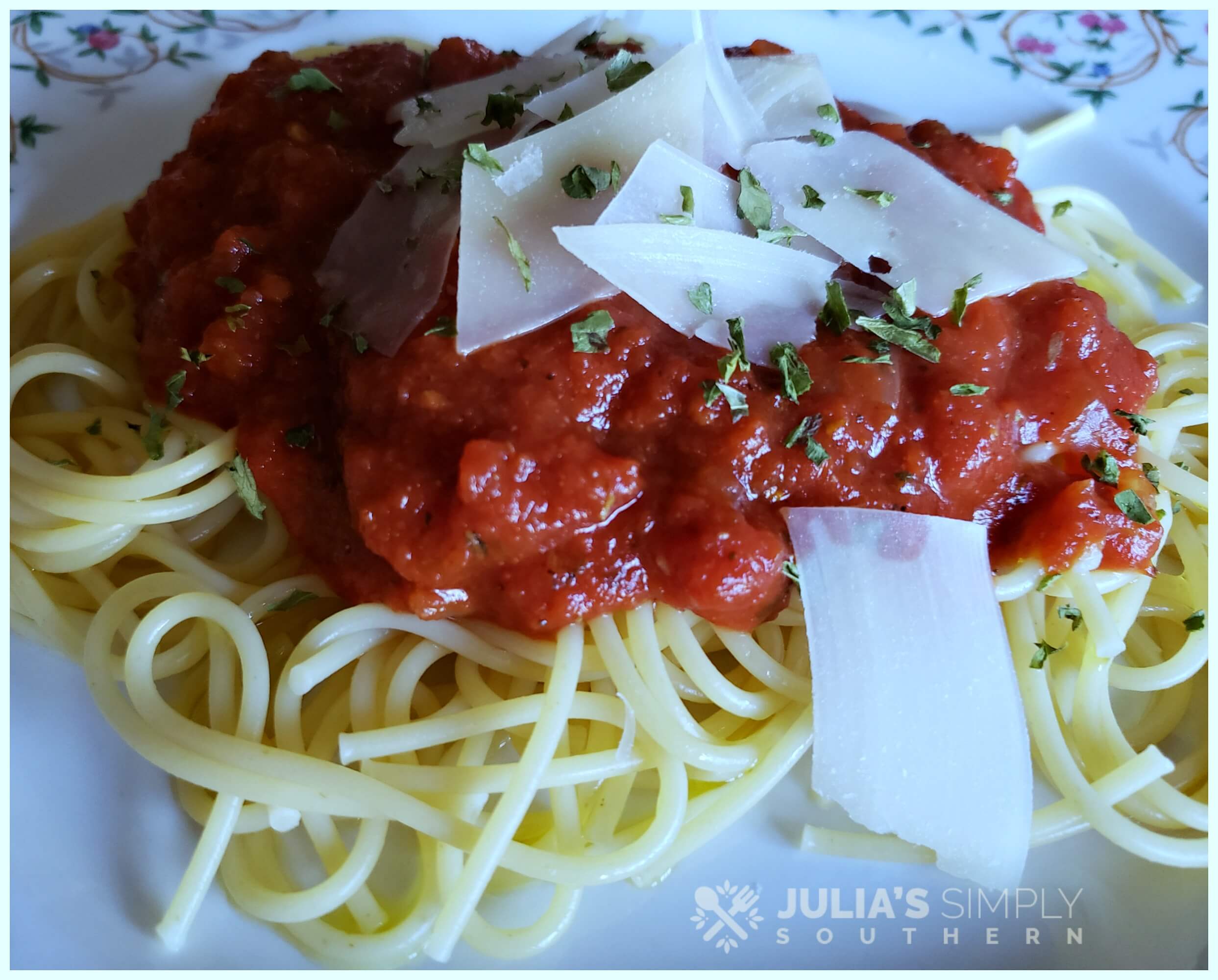 Spaghetti with marinara and Parmesan on a floral china plate garnished with parsley