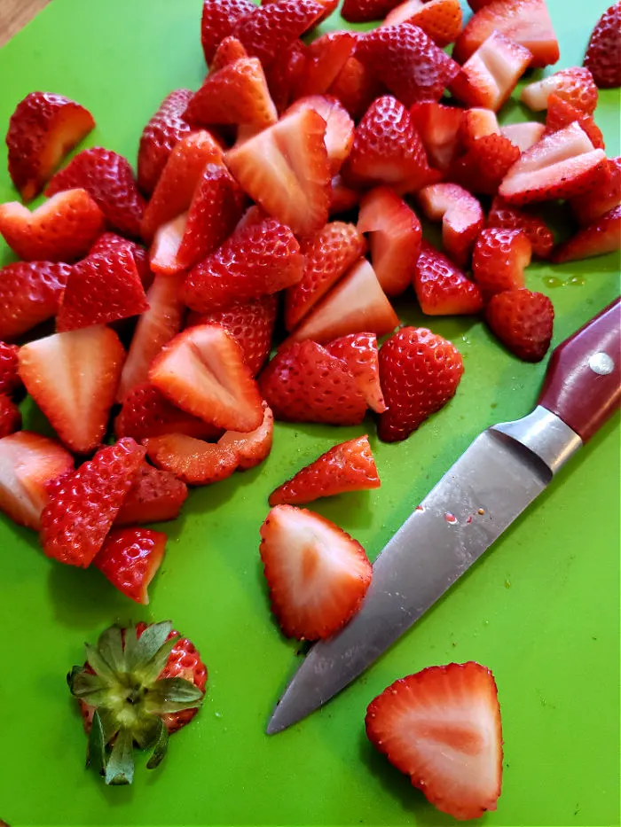 prepping fresh strawberries to make cheesecake topping sauce