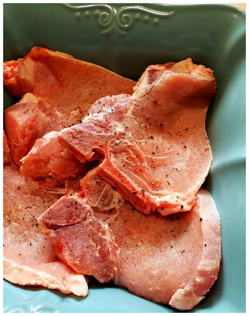 Bone in pork chops in a teal casserole dish