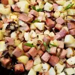 Cast iron skillet with diced potatoes and Spam with onion
