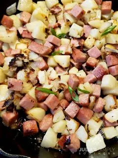 Cast iron skillet with diced potatoes and Spam with onion