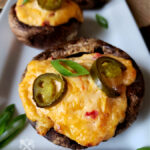 grilled pimento cheese Portobello caps on a serving platter garnished with scallions