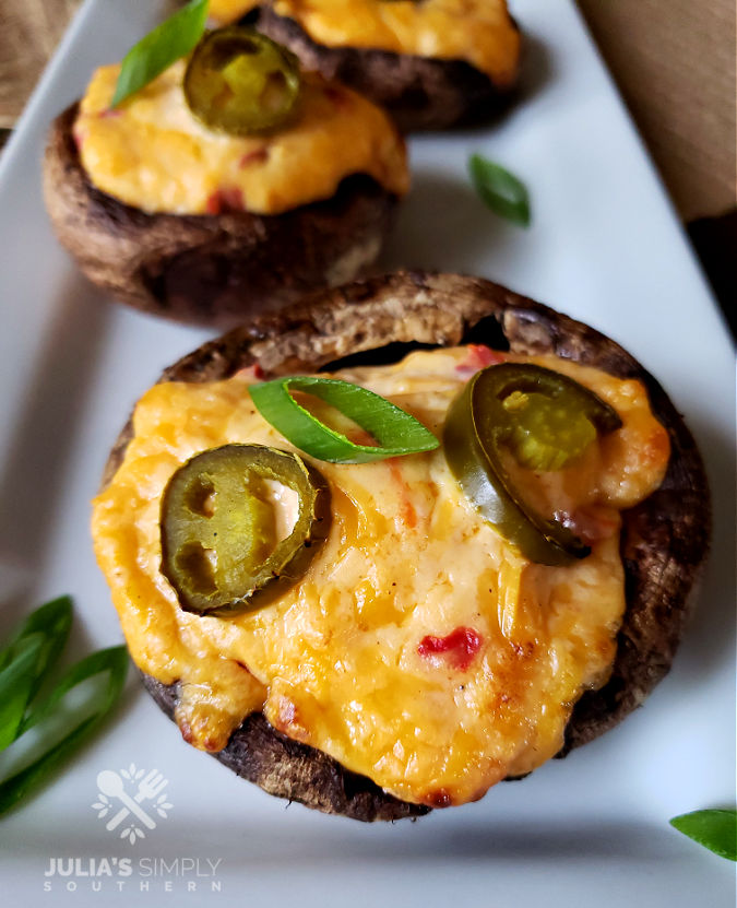 grilled pimento cheese Portobello caps on a serving platter garnished with scallions