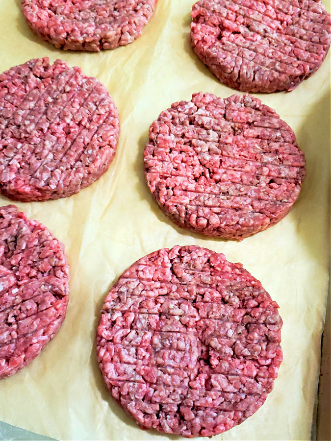 one third beef patties made with ground chuck beef on a parchment lined sheet pan