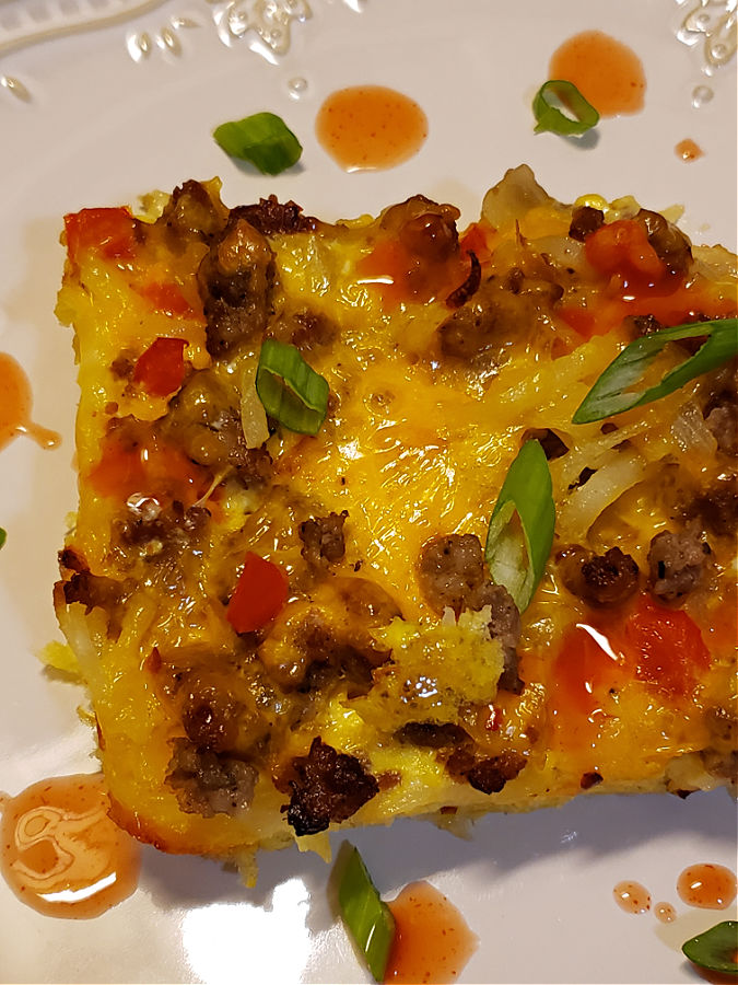 Breakfast Bake with shredded hash browns garnished with green onions and hot sauce