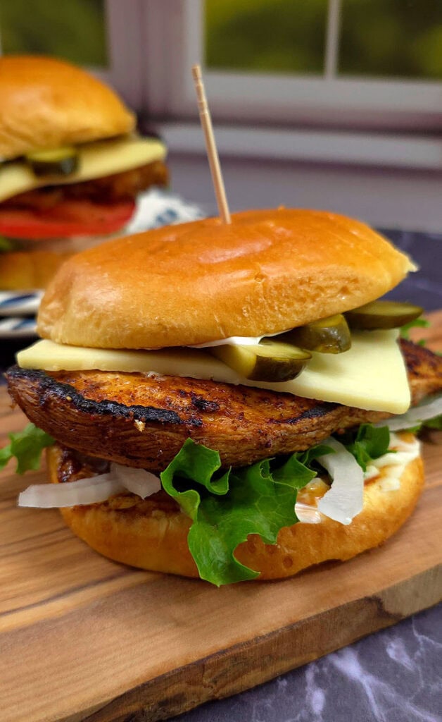 Blackened chicken sandwich on a bun served on a blue and white plate.