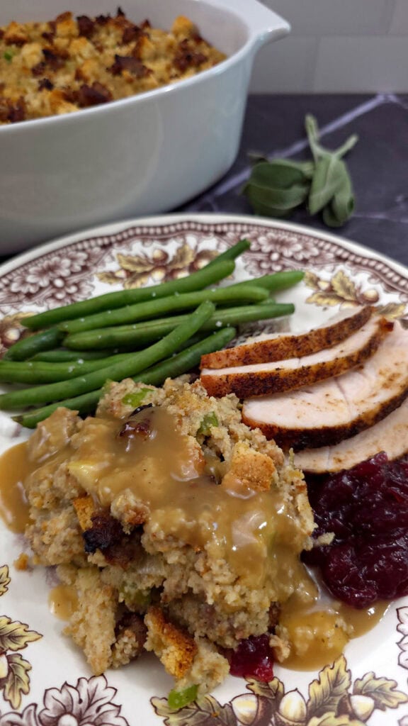 Southern cornbread dressing with apples and sage served with roasted turkey and string beans on a Thanksgiving China plate
