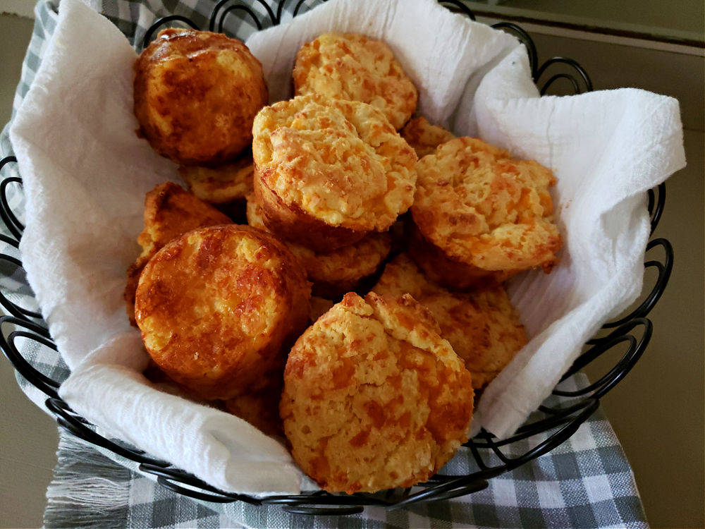 Basket lined with flour sack towel filled with cheddar sour cream biscuits