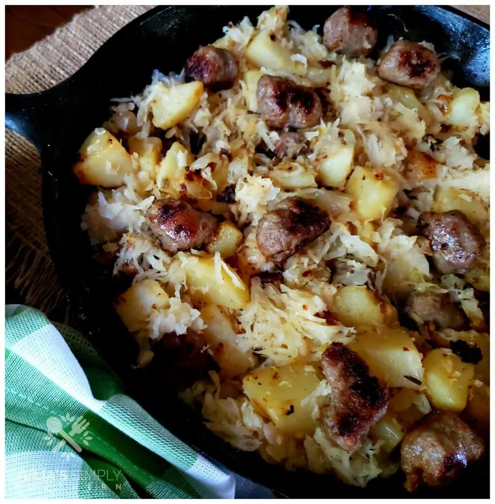 Black cast iron skillet filled with sausages and diced potato