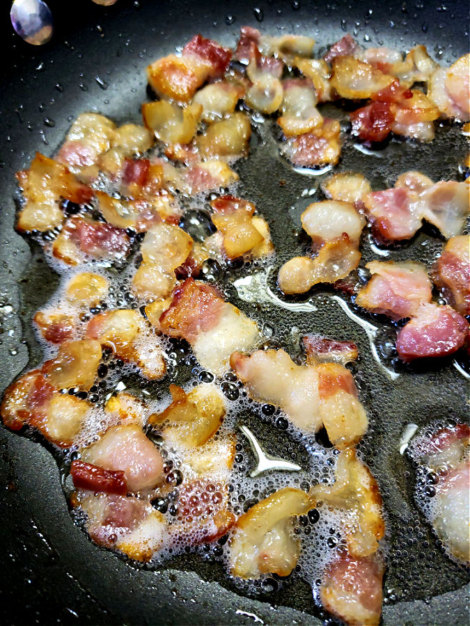 chopped bacon being sautéed in a skillet