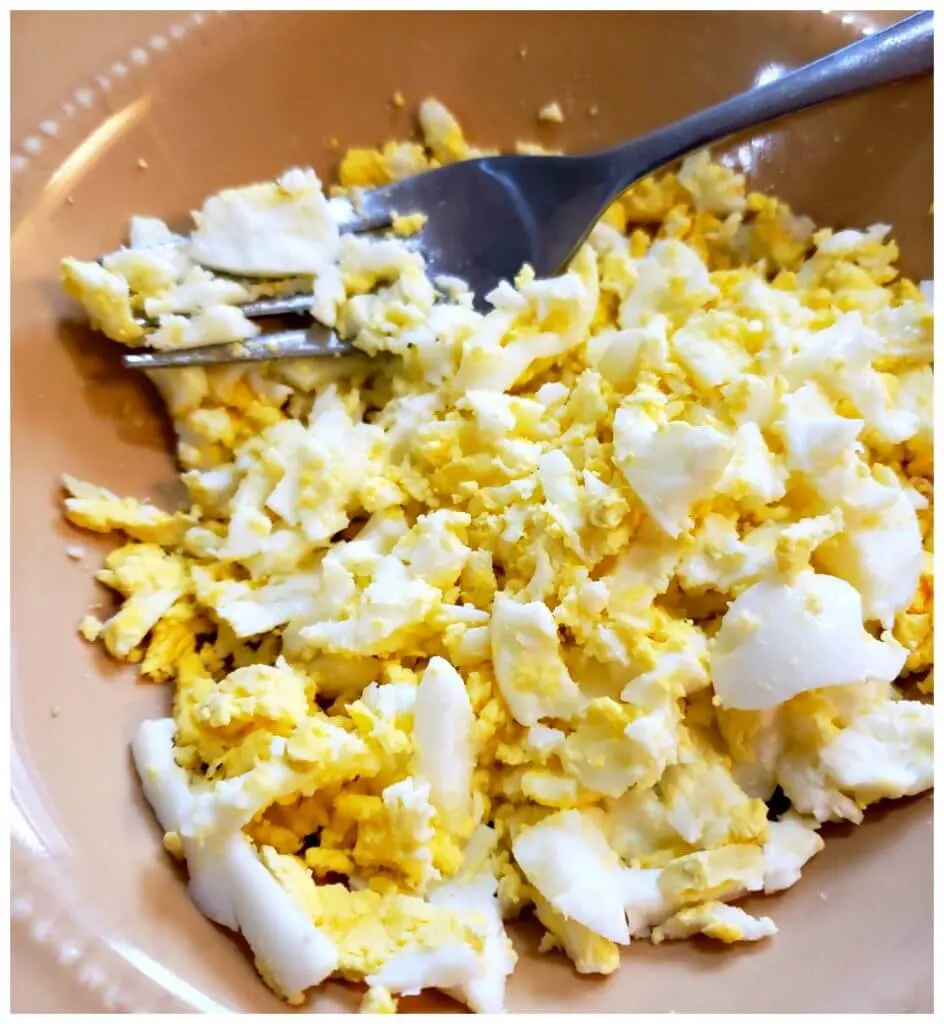 Mashing up boiled eggs for egg salad in a bowl