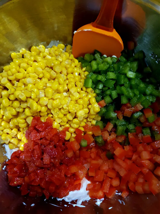 Mixing up the corn dip in a stainless mixing bowl