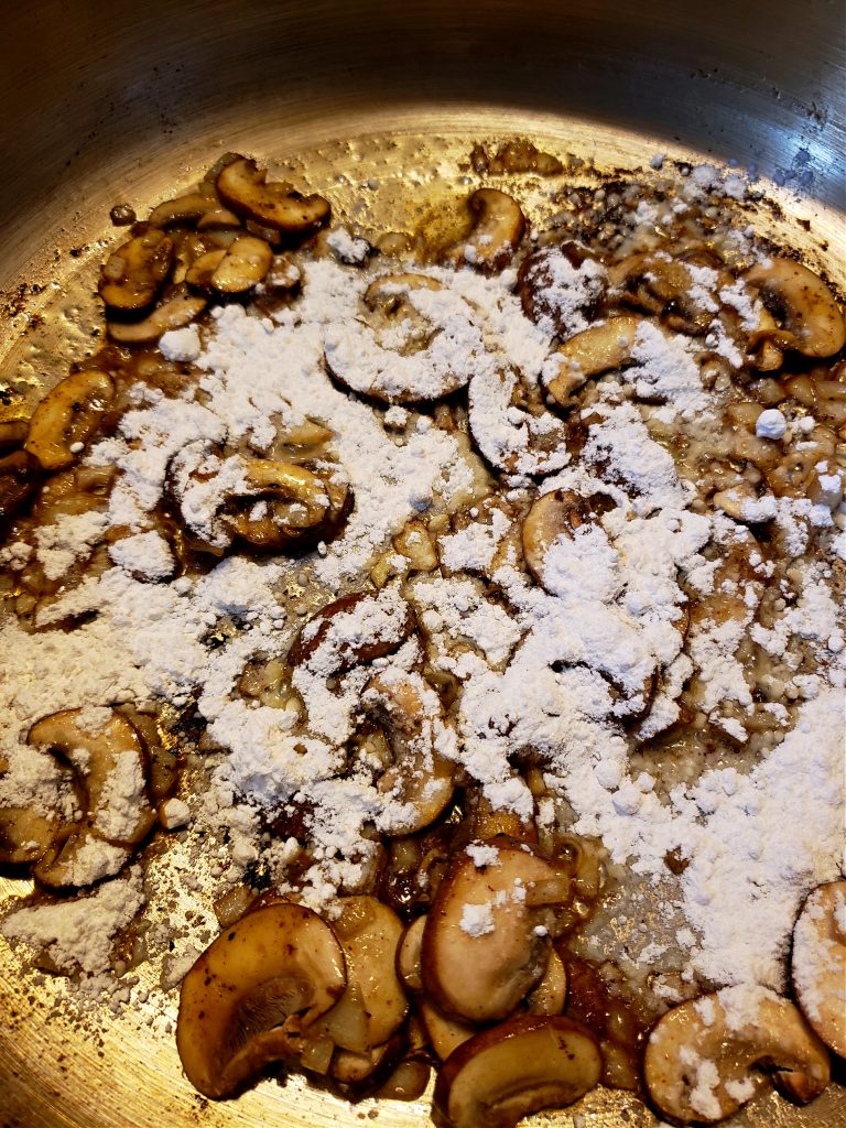 Adding flour to mushrooms to make gravy