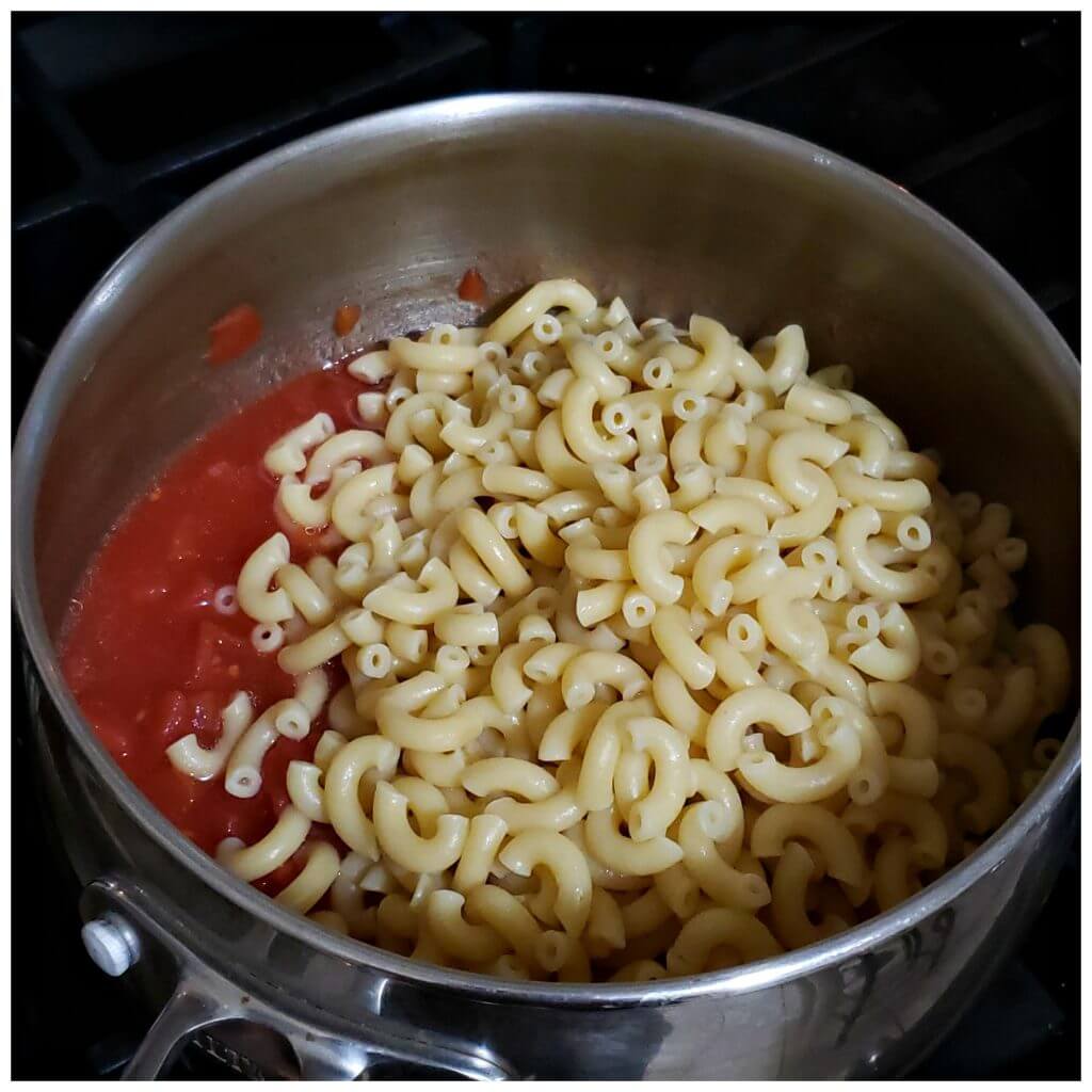 Stainless cooking pot with stewed tomatoes and cooked elbow macaroni pasta