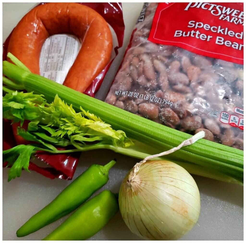 White cutting board with a package of speckled butter beans, vegetables and smoked sausage