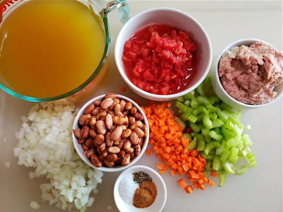 white cutting board with the ingredients assembled to prepare cranberry bean soup with sausage