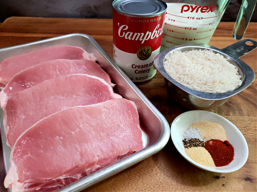 ingredients to prepare a baked pork chops and rice casserole on a cutting board