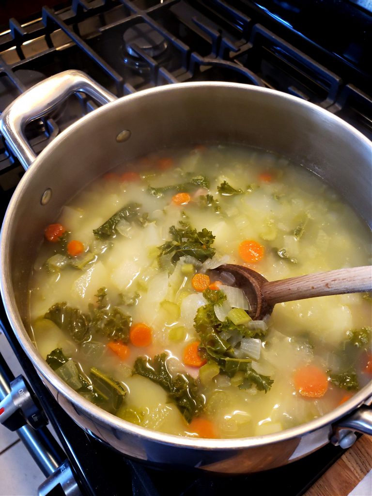 Silver Biltmore Stainless soup pot with ham potato kale soup recipe simmering on a gas stove top