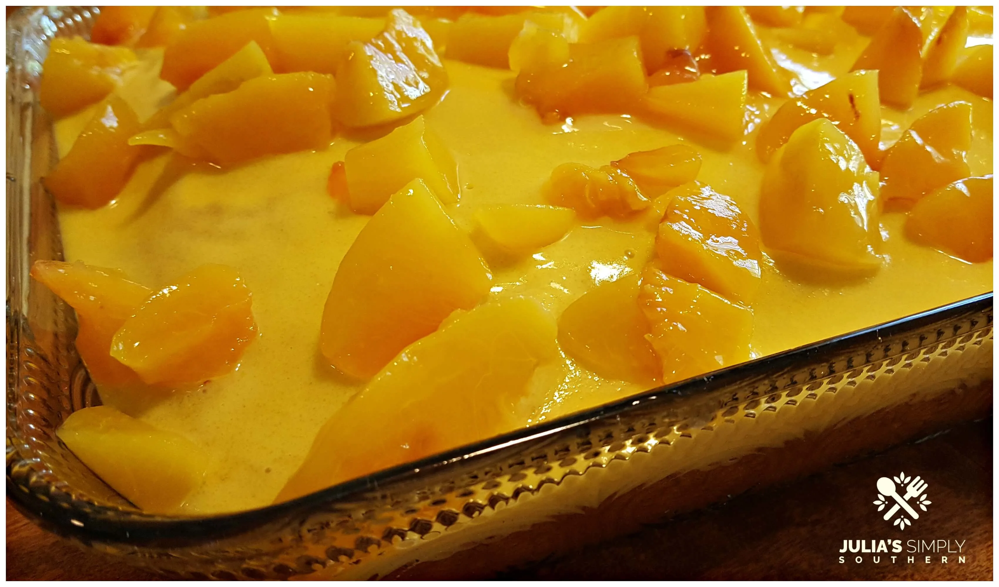 Layering peach over a poke cake in a Pioneer Woman glass casserole dish