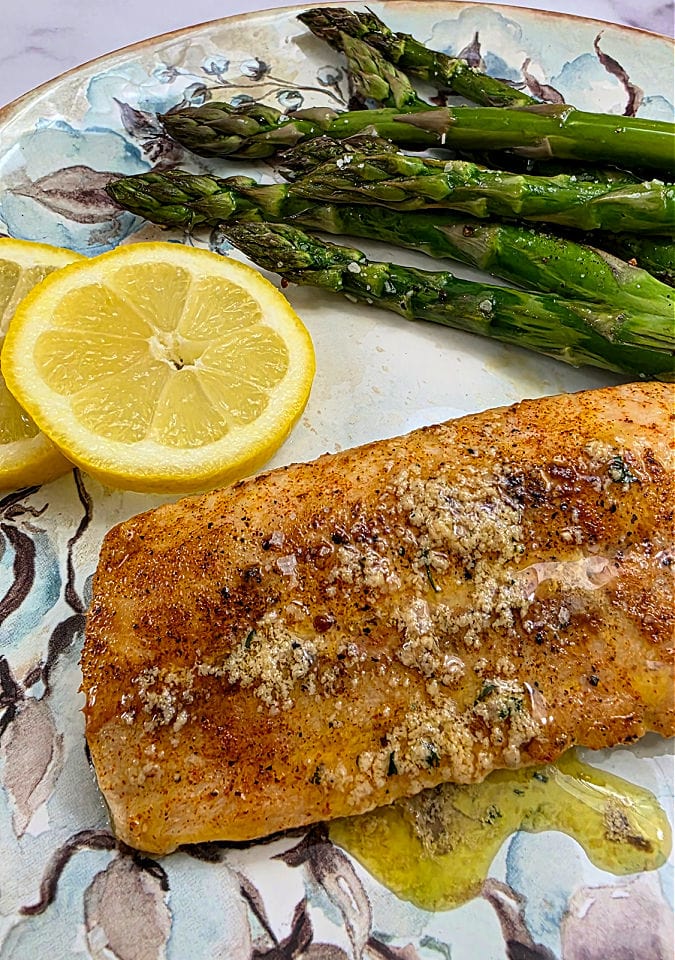 A plate with blackened mahi mahi, asparagus and lemon.