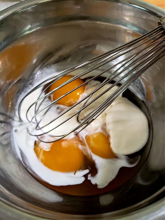 3 duck eggs with ricotta cheese and heavy cream in a meatal mixing bowl