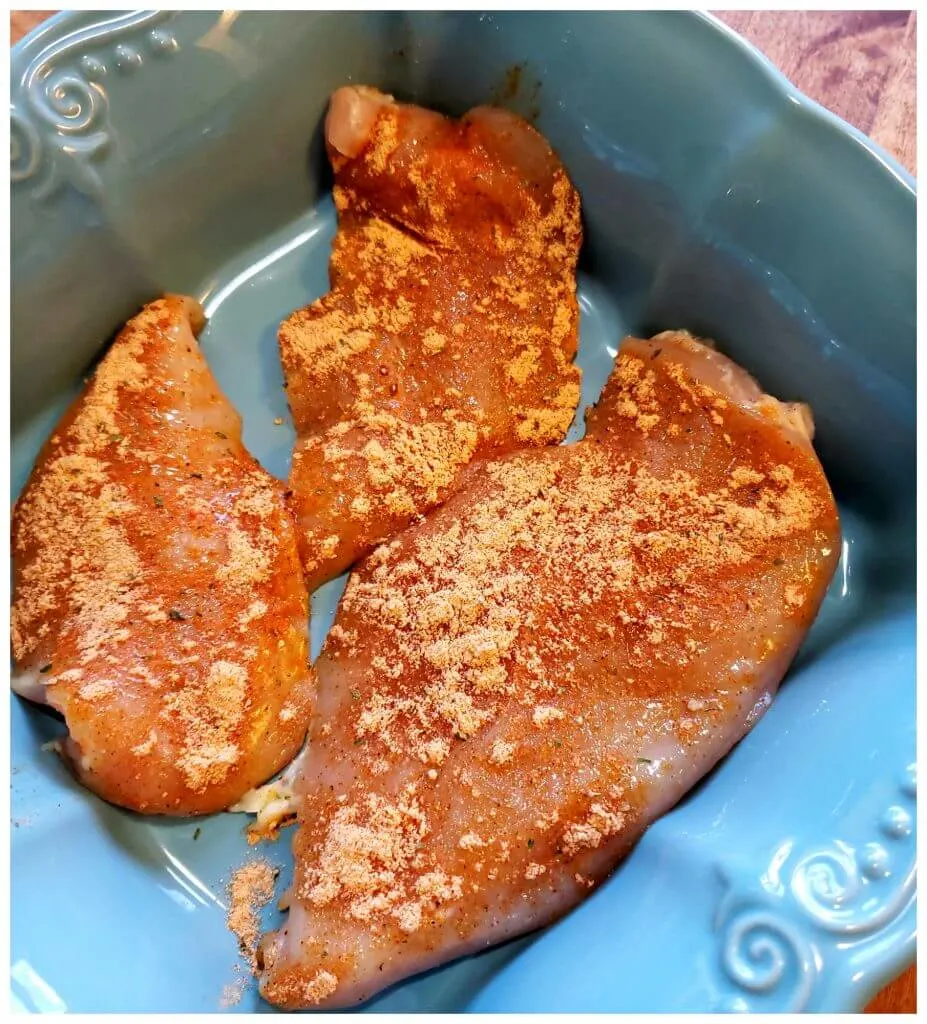 Teal baking dish with chicken breast ready to go into an oven