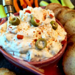 Classic cream cheese and green olives spread appetizer served with crackers and crudités